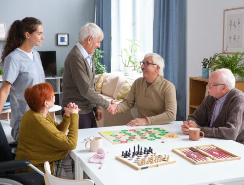 Senior man greeting his friends in the room, they gathering to play board games together